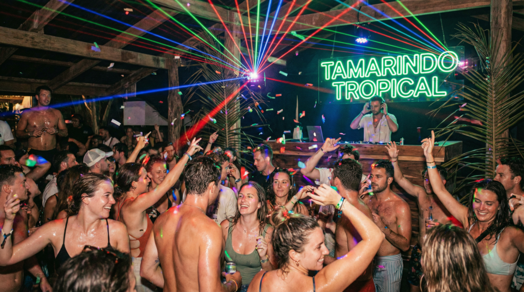 A high-energy dance club in Tamarindo with a crowd of people dancing under colorful laser lights.