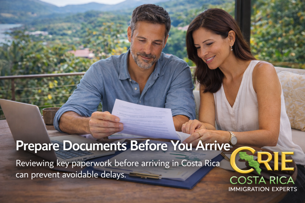 Couple reviewing investor residency paperwork at an outdoor table in Costa Rica with a laptop, with an overlay reminding them to prepare documents before arriving