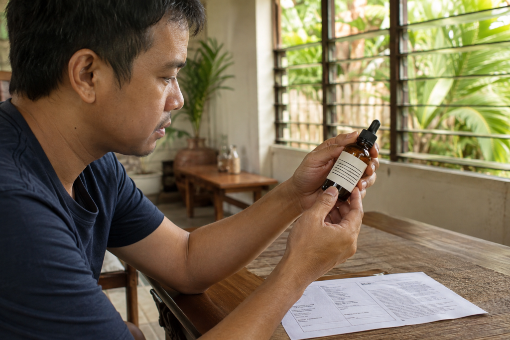 An adult reviews a small product bottle and its packaging indoors.