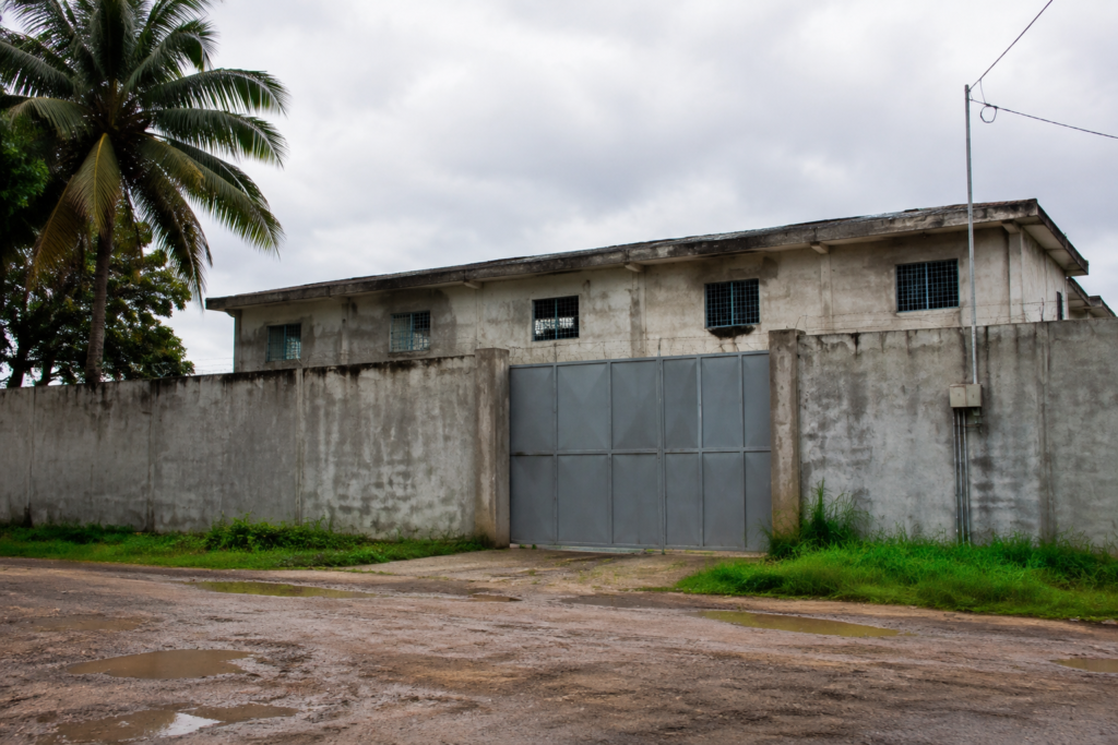 A low-rise secured building behind a perimeter fence.