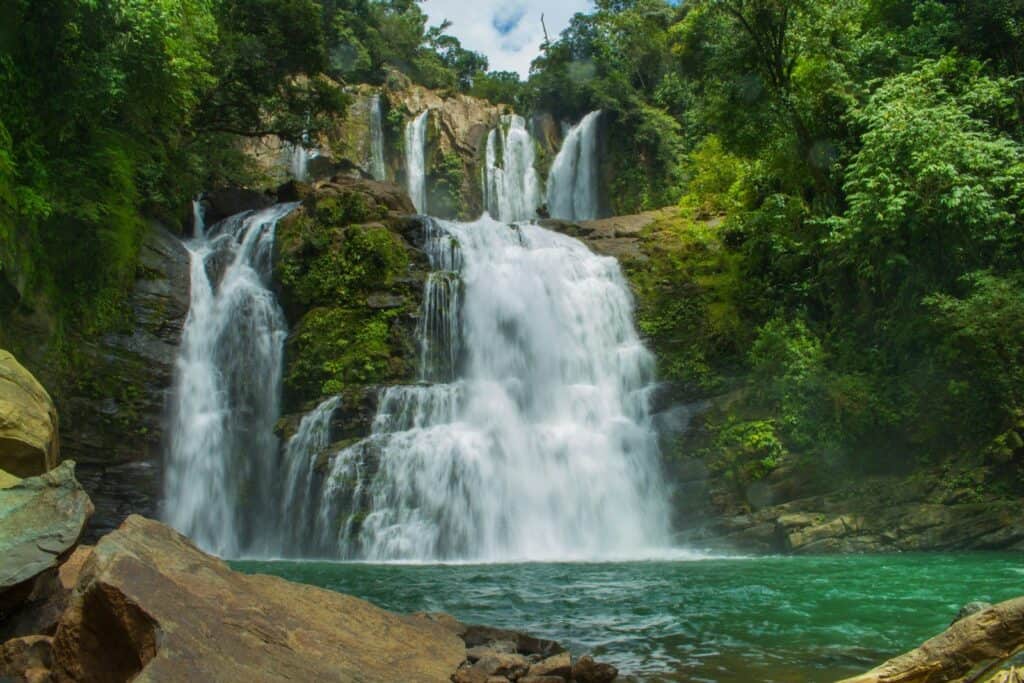 Nauyaca Waterfalls dropping in two tiers into a green pool near Dominical, Costa Rica